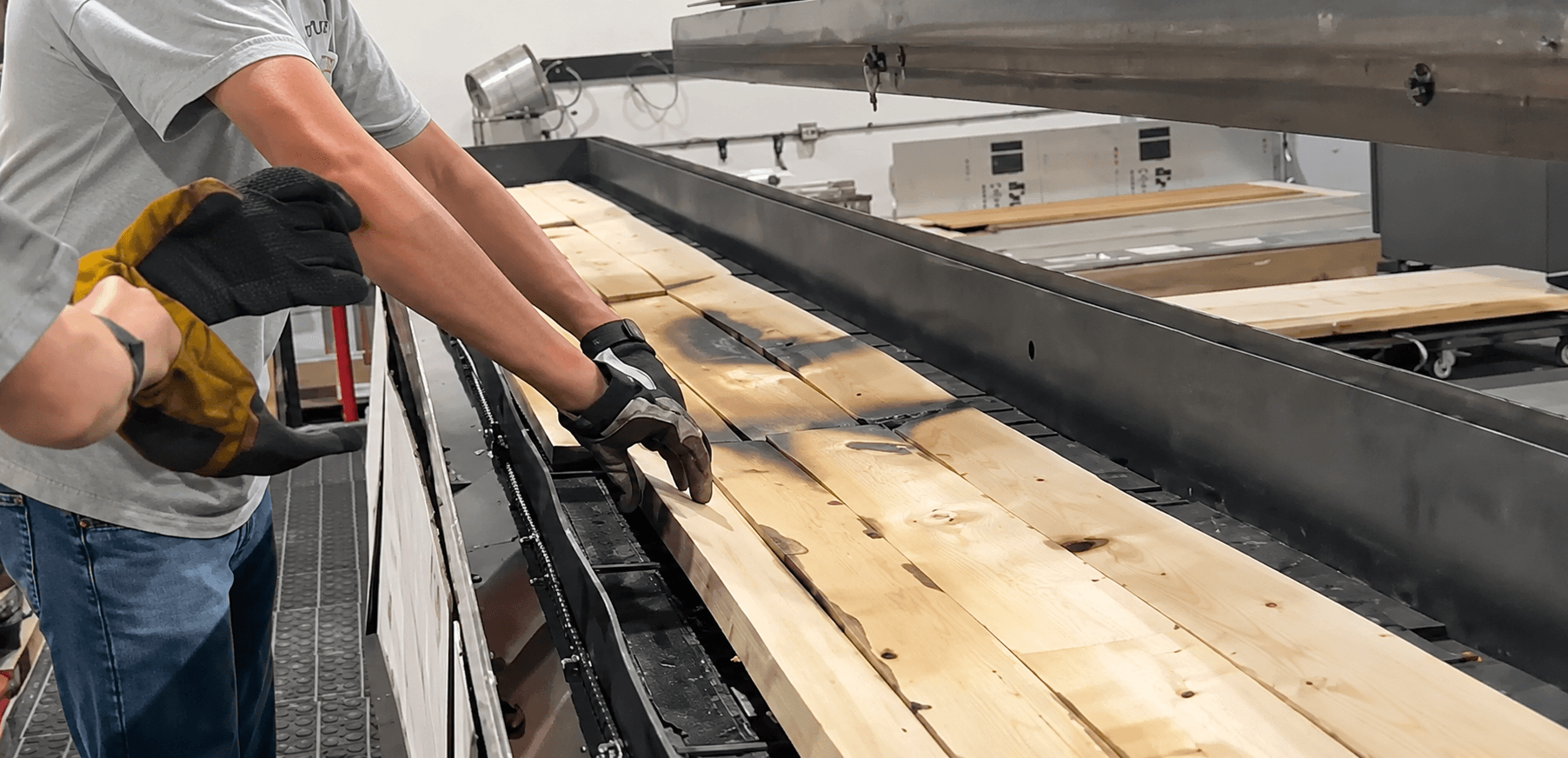 A worker handling paulownia boards showing surface char from fire testing